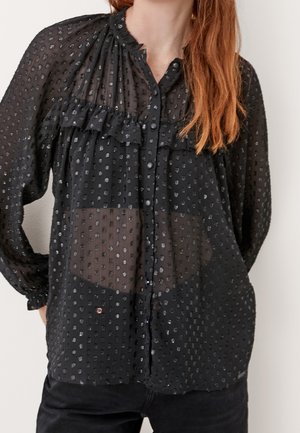 Schwarze transparente Bluse mit Rüscheneinsatz, gepunkteter Textur, Knopfverschluss und langen Ärmeln. Die Vorderseite weist ein schichtartiges Design und leichte Durchsichtigkeit auf.