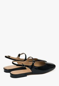 Zwarte gepatineerde leren slingback schoenen met een spitse neus, platte hak en verstelbare enkelband. Glad materiaal met minimale ontwerpdetails.