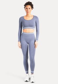 Blå langærmet crop top med rund halsudskæring og matchende højtaljede leggings med hvide stribede detaljer ved kanterne.