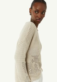 Strickpullover in Cremefarbe mit einer Mischung aus engen und offenen Webmustern, Rundhalsausschnitt und langen Ärmeln mit strukturierten Akzenten.