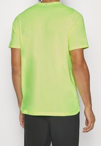 Camiseta atlética de manga corta verde neón con cuello redondo, textura suave y acento reflectante cerca del escote. Diseño sencillo, sin patrones.