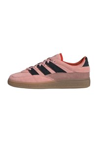Pink suede sneakers with black leather stripes, textured rubber sole, and red accents on the interior and tongue. Adidas logo on side.