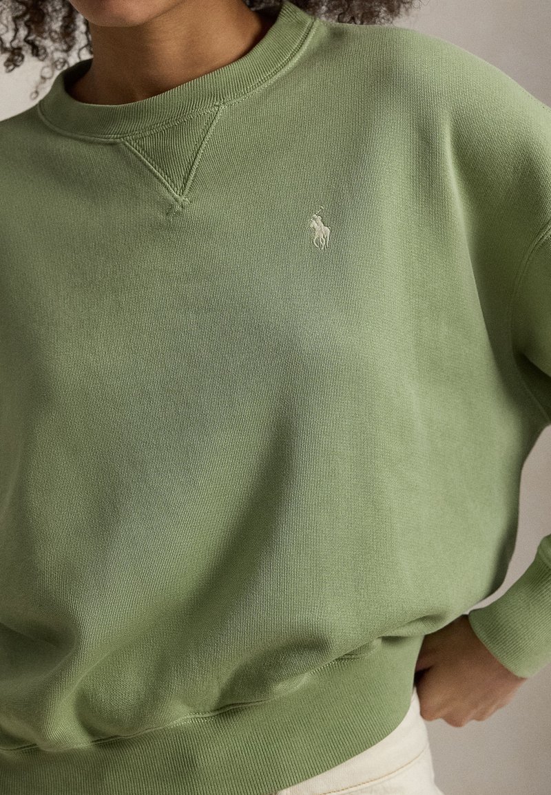 Green sweatshirt made of soft cotton with a crew neckline, ribbed cuffs, and a small white logo on the chest.