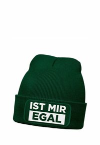 Green knitted beanie with a ribbed texture, featuring a white rectangular patch printed with "IST MIR EGAL" in bold black letters.