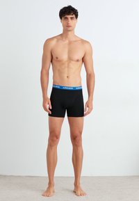 Schwarze Boxershorts für Männer mit einem blauen Bund, gefertigt aus elastischem Material. Die Passform ist enganliegend und das Design ist nahtlos.