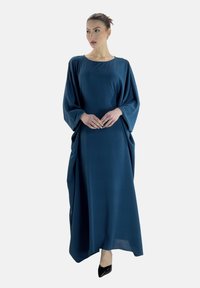 Lungo vestito blu, ampio e sciolto, con maniche larghe e scollo arrotondato, realizzato in tessuto liscio, con una lunghezza fino al pavimento e un drappeggio sottile.