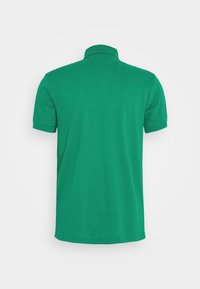 Polo vert à manches courtes montré de dos avec un col et une texture de tissu unie et lisse.