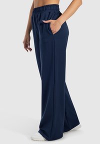 Marineblauwe wijde broek gemaakt van zachte stof, met een elastische tailleband, zijzakken en subtiele geborduurde logo-details.