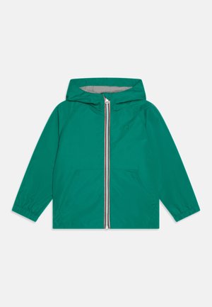 Veste à capuche verte en matériau léger, avec une fermeture éclair complète à l'avant ornée d'une bande rouge et blanche, et deux poches avant.