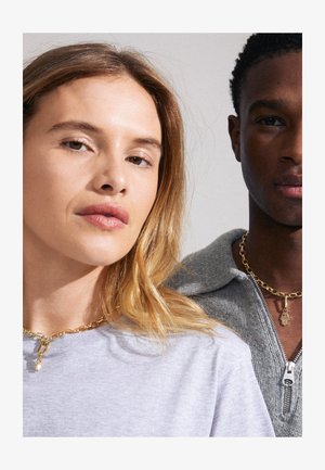 Du žmonės dėvi auksines grandinėles. Vienas turi šviesiai pilką marškinį, o kitas vilki pilką užtraukiamą džemperį.