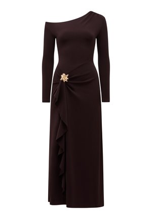 Asymetrické dlhé čierne šaty s jedným ramenom, bočným volánom a ozdobnou zlatou kvetinovou brošňou na páse.