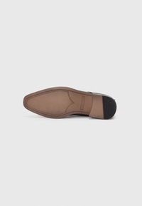 Suela de zapato de cuero marrón con un diseño puntiagudo, que presenta una superficie lisa y costuras en contraste a lo largo del borde, y acentos de goma para mayor tracción.