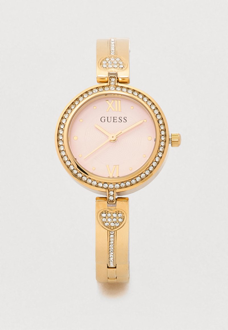 Guldur med rund urskive, lyserød skive og gyldne accenter. Har krystalpynt og et hjerteformet led i armbåndets design.