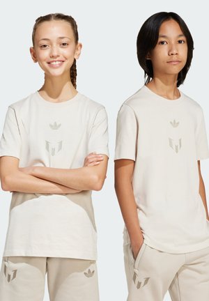 Beige puuvillapaidat minimalistisilla logoilla etupuolella, yhdistettynä vastaaviin beigeihin housuihin. Yksinkertainen, rento istuvuus mukavuutta varten.