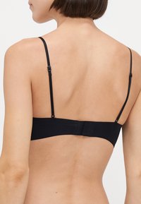 Soutien-gorge noir avec bretelles réglables, tissu lisse et fermeture à crochet au dos. Design simple sans embellissements visibles.