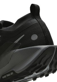 Black athletic shoe with textured mesh upper, gray accents, a rounded heel, and a patterned rubber outsole for traction. Nike Trail ATC branding displayed.