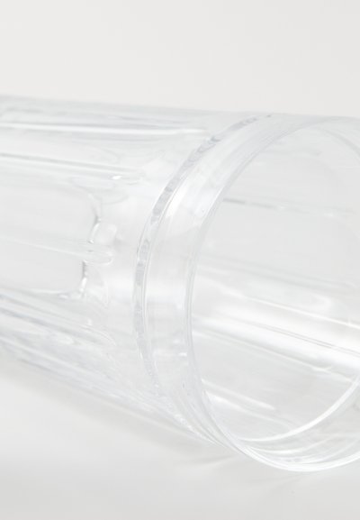Διαφανής πλαστικός κυπελλοειδής ποτήρι με κατακόρυφες ραβδώσεις, λείο χείλος και γυαλιστερή επιφάνεια. Ελαφρώς καμπύλο σχήμα, μίνιμαλ σχεδίαση χωρίς αξεσουάρ.