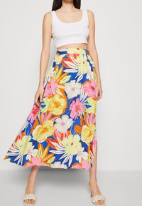 Kukallinen maksihame, jossa on sininen tausta ja eloisat vaaleanpunaiset, keltaiset ja valkoiset kukat, joustava vyötärö ja sivuhalkio. Yhdistetty valkoiseen toppiin.