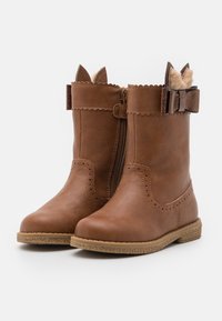 Brązowe, sztuczne skórzane botki za kostkę z zamkiem błyskawicznym z boku, falbaniastym wykończeniem górnym, akcentami w kształcie uszu kota oraz kokardką w okolicy kostki. Teksturowana podeszwa.