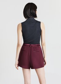 Un haut sans manches noir côtelé associé à un short bordeaux taille haute avec des accents en satin et deux poches arrière.