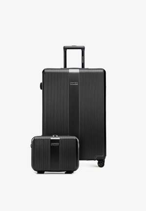 Due valigie rigide nere con linee verticali testurizzate, una grande con manico retrattile e quattro ruote, una più piccola senza manici visibili.