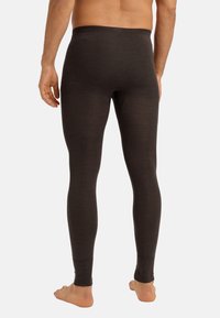 Dunkelbraune lange Leggings mit weicher Textur, elastischem Bund und figurbetontem Schnitt, entworfen für Komfort und Beweglichkeit.