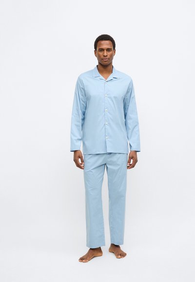 Svetlo modra pižama iz mehke tkanine. Srajca z dolgimi rokavi in z gumbi ter z zarezo ovratnika, kombinirana z hlačami z ravnimi hlačnicami.