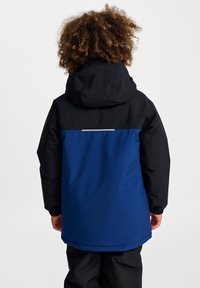 Veste imperméable avec capuche et manches noires, corps bleu, et accent réfléchissant dans le dos. Manches élastiques et design décontracté.