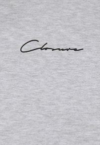 Grijze stof met een gladde textuur en een centraal geplaatste zwarte cursieve logo, "Chlorure".