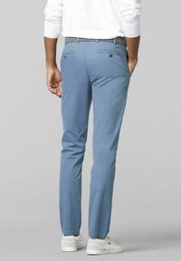 Pantaloni dritti blu chiaro con una texture liscia. Presentano tasche posteriori, una cintura intrecciata e un design a gamba affusolata. Indossati con sneakers bianche.