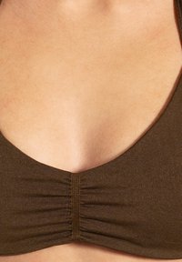 Bralette de tejido marrón texturizado con un escote en V profundo y centro recogido. Bordes suaves y diseño minimalista. Sin herrajes visibles.