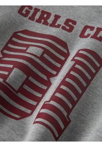 Szara bawełniana koszulka z wyrazistym bordowo-paskowanym napisem "GIRLS CL" i liczbą "91" o teksturowanej powierzchni.