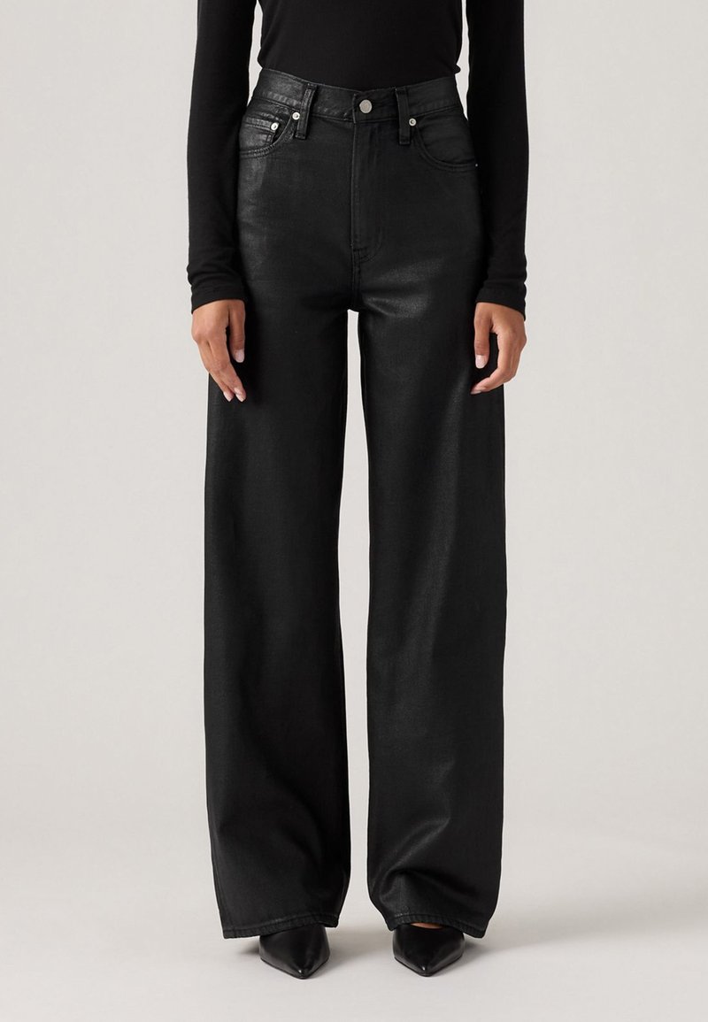 Zwarte wijde jeans van denim, met een hoge taille, sluiting met een knop aan de voorkant en een minimalistisch design, gecombineerd met puntige schoenen.