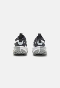Black and gray athletic shoes with a textured upper, white accents, and a flexible sole featuring distinct tread patterns.