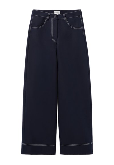 Pantalons large en navy en tissu avec des coutures blanches contrastantes, présentant des poches avant et une fermeture à bouton à la taille.