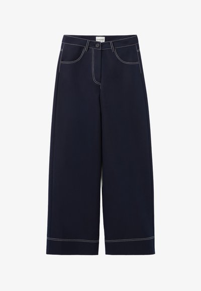 Pantalons large en navy en tissu avec des coutures blanches contrastantes, présentant des poches avant et une fermeture à bouton à la taille.
