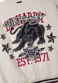 Black panther with claws extended, surrounded by black stars and red text "Ed Hardy" and "EST. 1971" on white fabric.