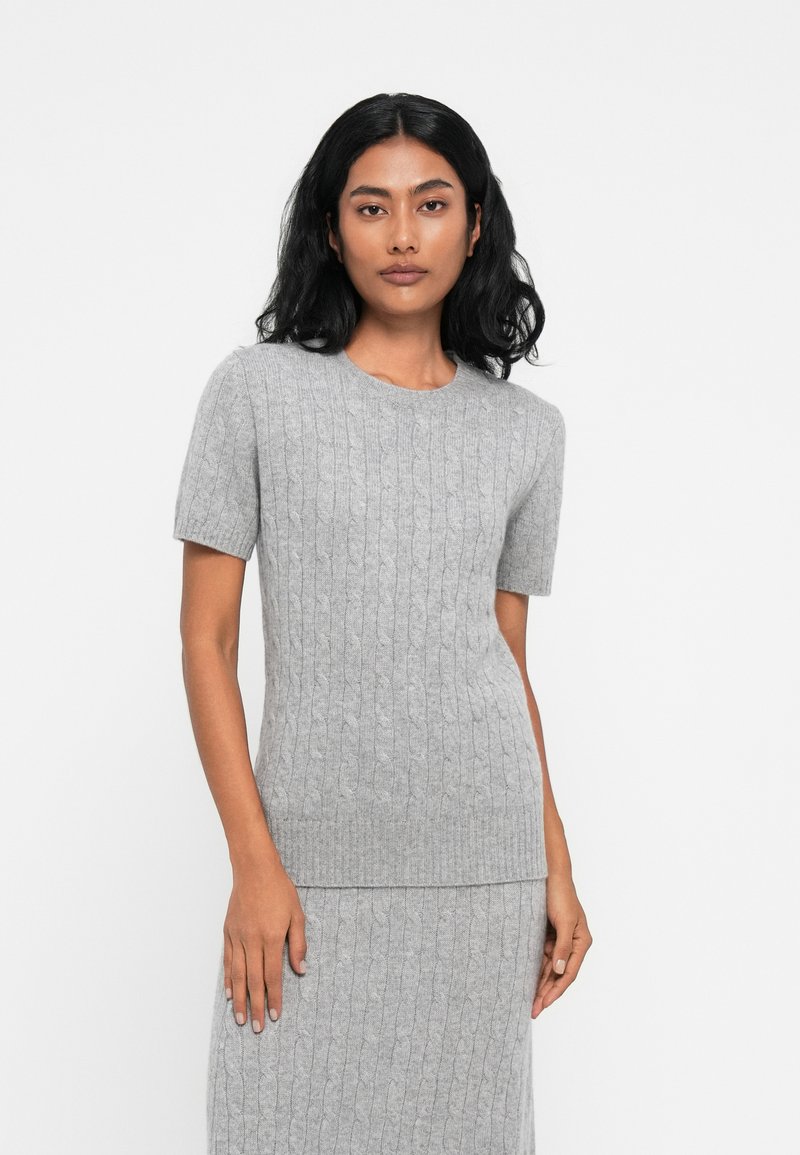 Maglione grigio a coste con maniche corte, scollatura rotonda e motivo testurizzato, abbinato a una gonna a coste coordinata.