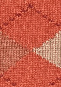 Tessuto lavorato a maglia con un design geometrico nei colori arancione, beige e crema. Superficie testurizzata con cuciture visibili e motivi a rombo.