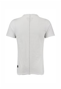 Camiseta blanca de manga corta vista desde la parte de atrás con una costura vertical visible que recorre el centro.
