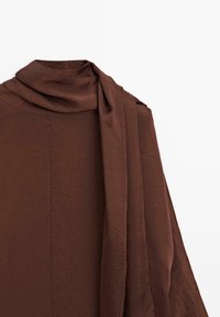 Bruine textuurstof met een zachte val, featuring een geplooide halslijn en een lange, vloeiende accentstuk aan één zijde.