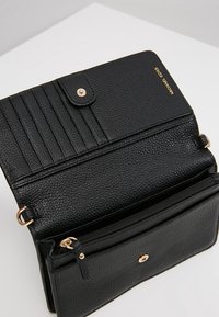 Sort læderpunge med en struktureret overflade, der har flere kortpladser, en lynlåslomme og hardwaredetaljer i guldfarve.