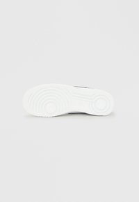 Nike sportcipő talpa, fehér gumi, kör alakú mintákkal és texturált tapadással. Tiszta kialakítással, lekerekített élekkel és bevágott logórésszel rendelkezik.