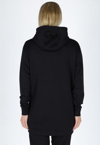Sort hættetrøje med et rummeligt design, blød tekstur og snoretræk i hætten. Lange ærmer og en længere bagkant giver ekstra dækning.