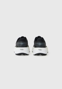 Pair of black and white New Balance running shoes with Fresh Foam midsoles, viewed from the back against a plain background.