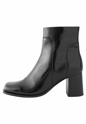 Stivale alla caviglia nero in pelle lucida, con punta quadrata, tacco a blocco e una delicata cucitura per un design minimale.