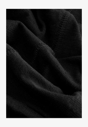 Črn material z gladko teksturo, ki vsebuje subtilne gube, fini pleten vzorec in rafinirane šive ob robovih.