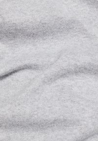 Vaaleanharmaa kangas, jossa on pehmeä, teksturoitu neulonta. Sen pinnassa on sileä pinta, jossa on hienovaraisia sävyvaihteluita, eikä näkyviä kuvioita tai koristeita.