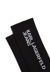 Svarta ribbade strumpor med texten "KARL LAGERFELD JEANS" i vita broderade bokstäver. Slät textur med en tät passform.