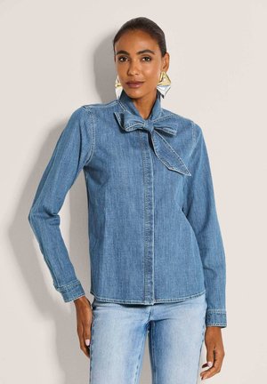 Jeanshemd mit langen Ärmeln, hellblau, mit Schleifenkragen und Knopfleiste, kombiniert mit hellblauen Jeans.